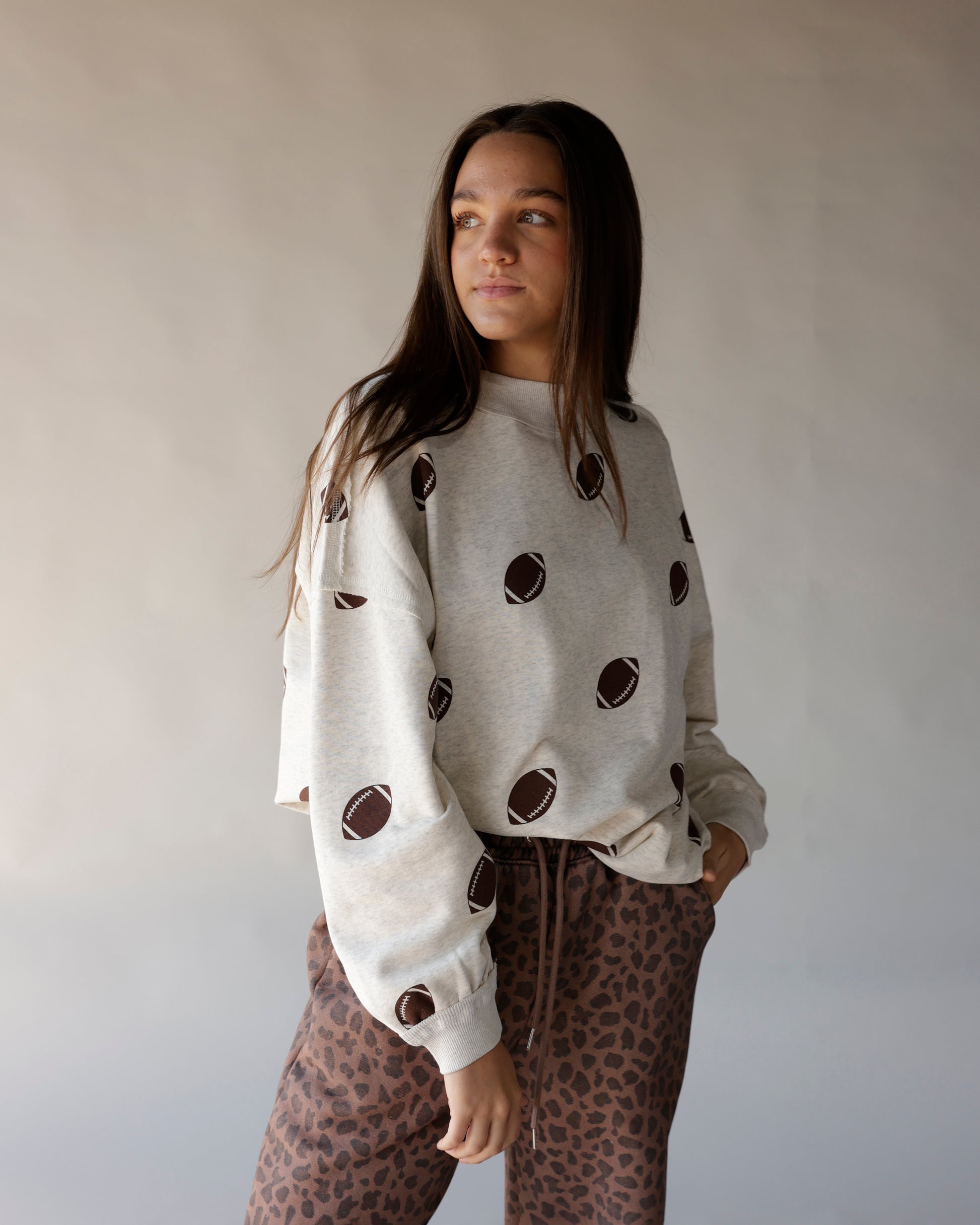 Heather gray crewneck sweatshirt with all-over brown football print pattern