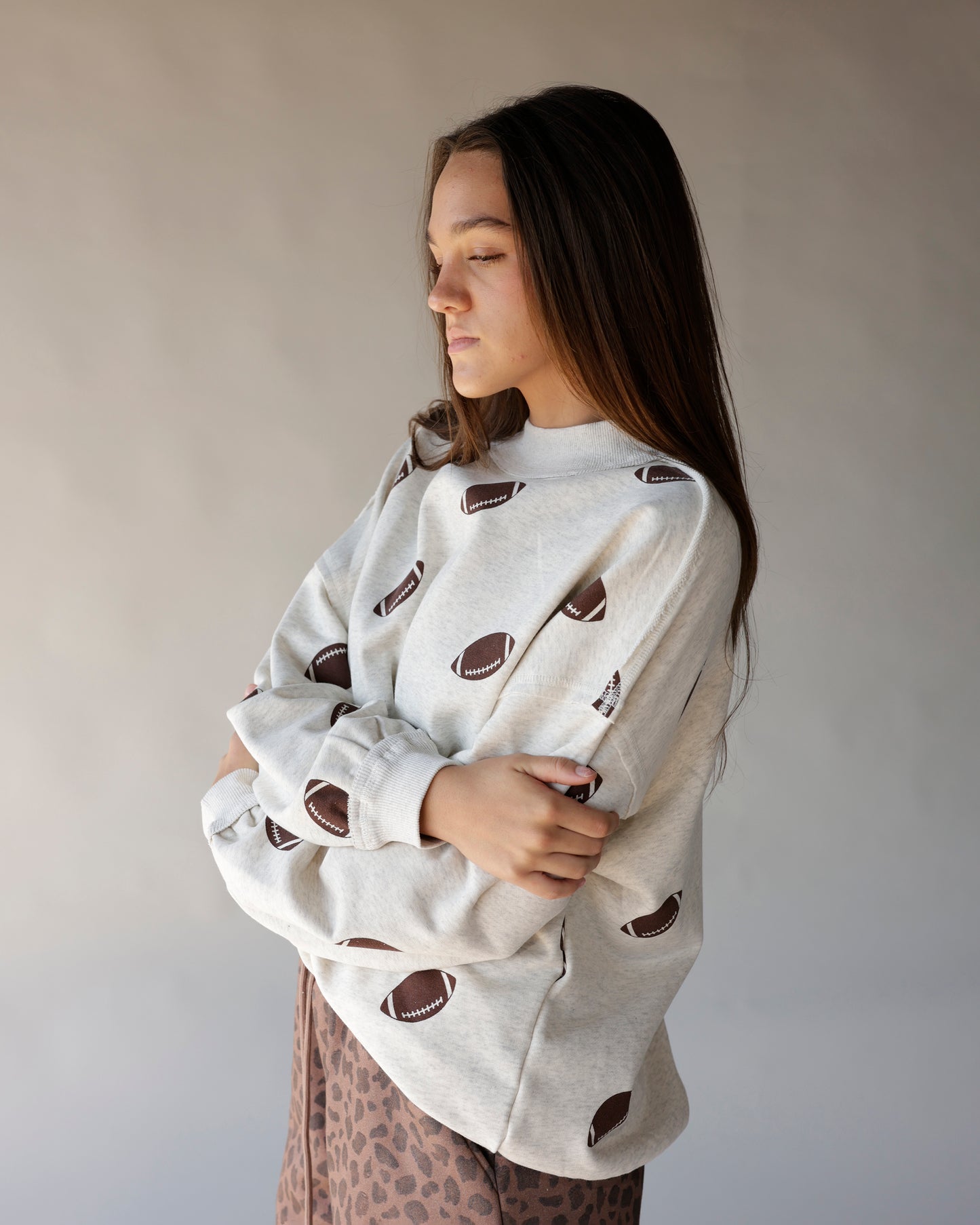 Oatmeal mock neck sweatshirt with allover brown football print, oversized fit