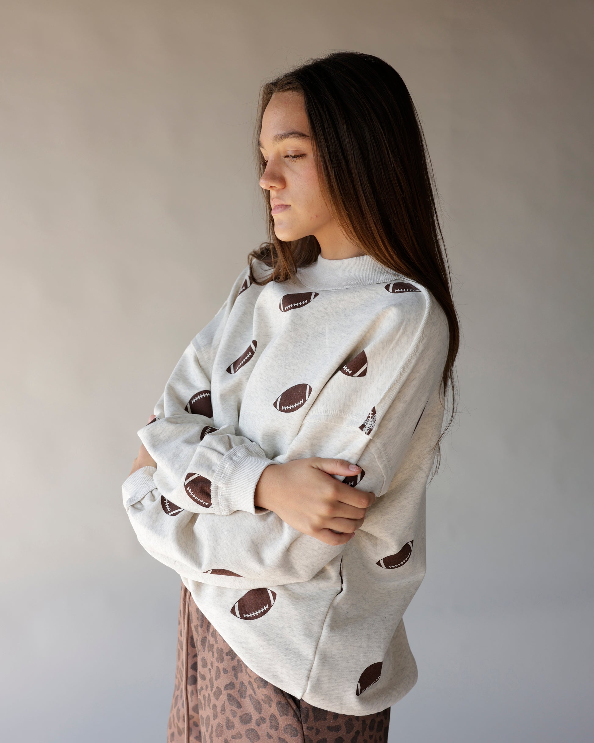 Oatmeal mock neck sweatshirt with allover brown football print, oversized fit