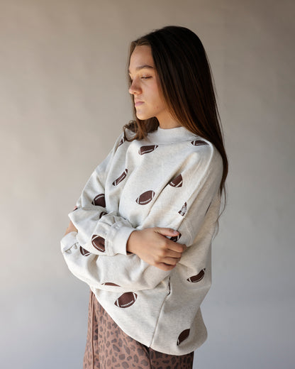 Oatmeal mock neck sweatshirt with allover brown football print, oversized fit