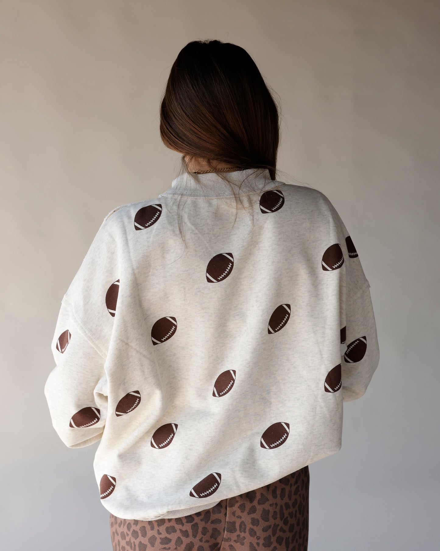 Cream heathered mock neck sweatshirt with allover brown football print, back view