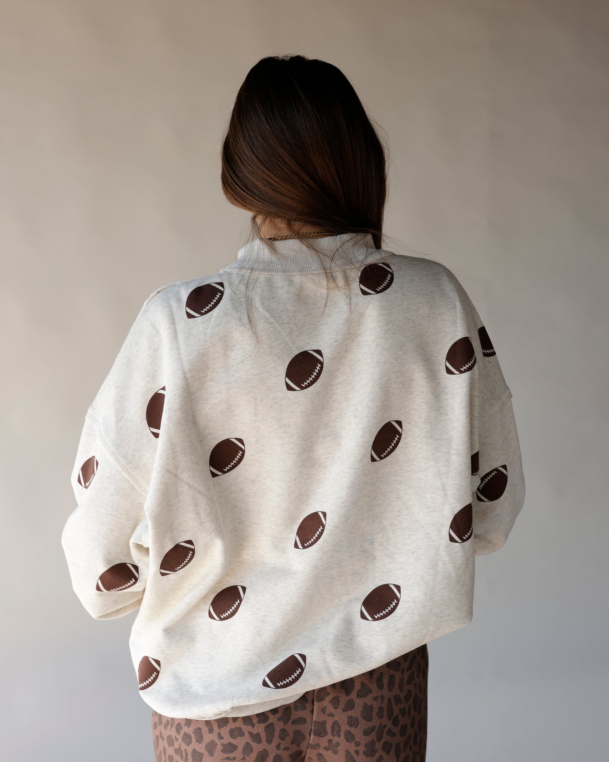 Cream heathered mock neck sweatshirt with allover brown football print, back view
