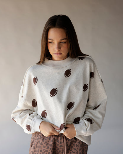 Oatmeal mock neck sweatshirt with all-over brown football print, oversized fit