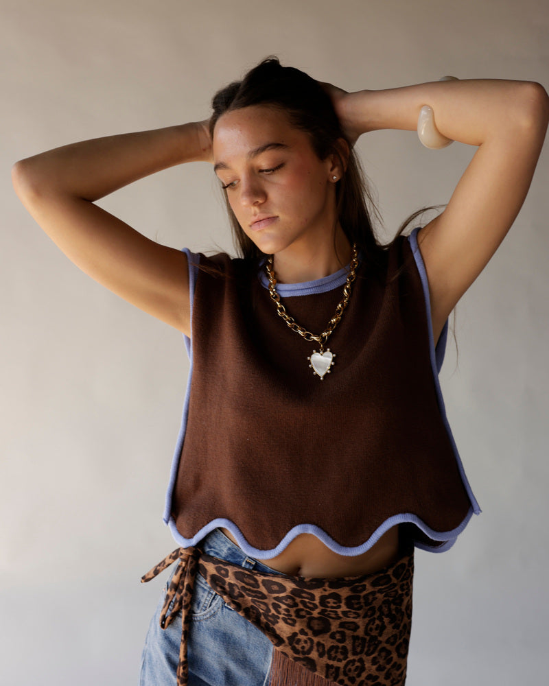 Brown cropped knit vest with wavy blue trim worn over blue crop top