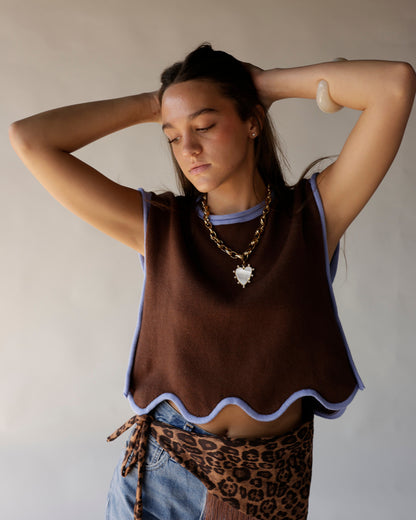Brown cropped knit vest with wavy blue trim worn over blue crop top