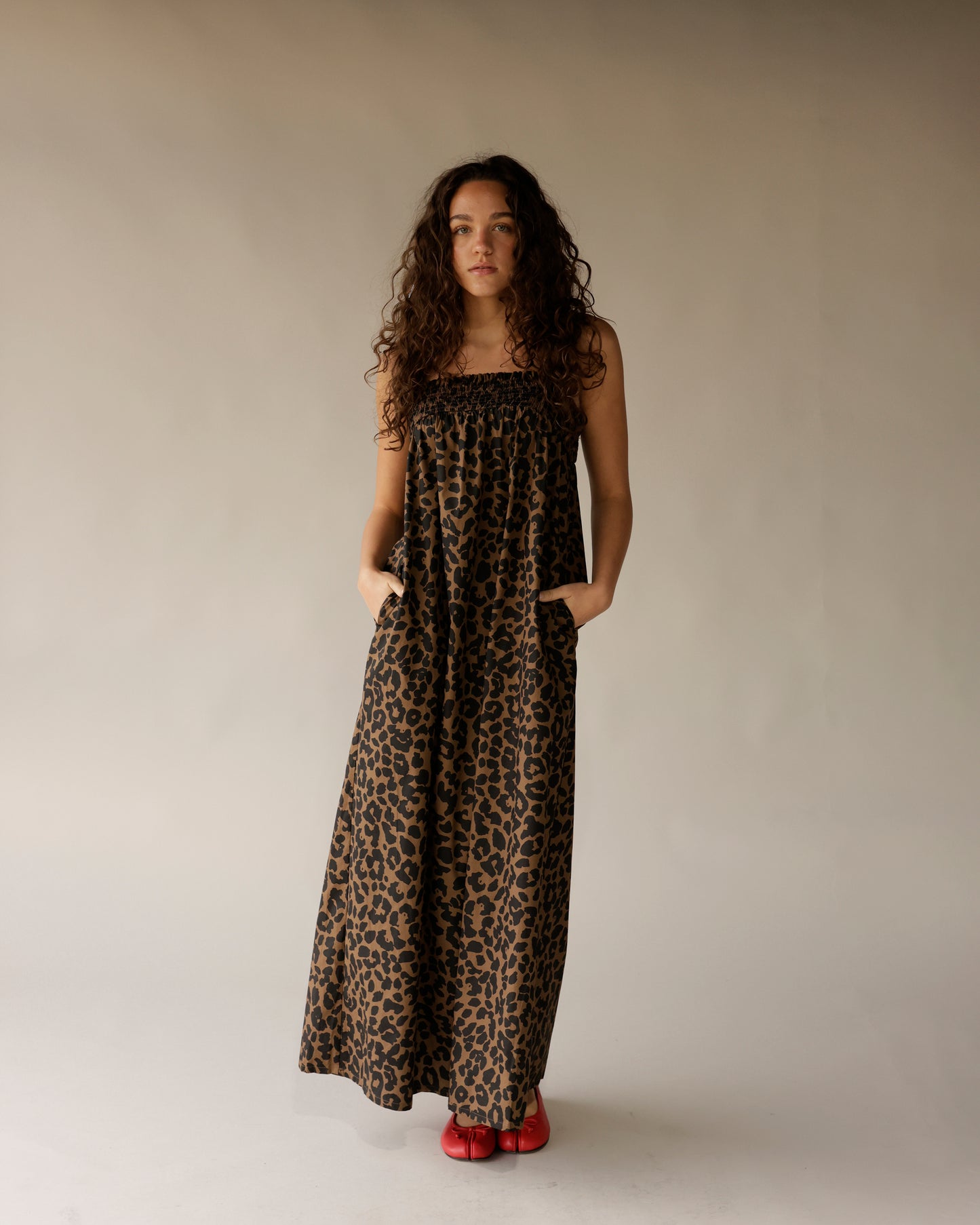 Leopard print strapless maxi dress with smocked bodice and pockets, styled with red flats.