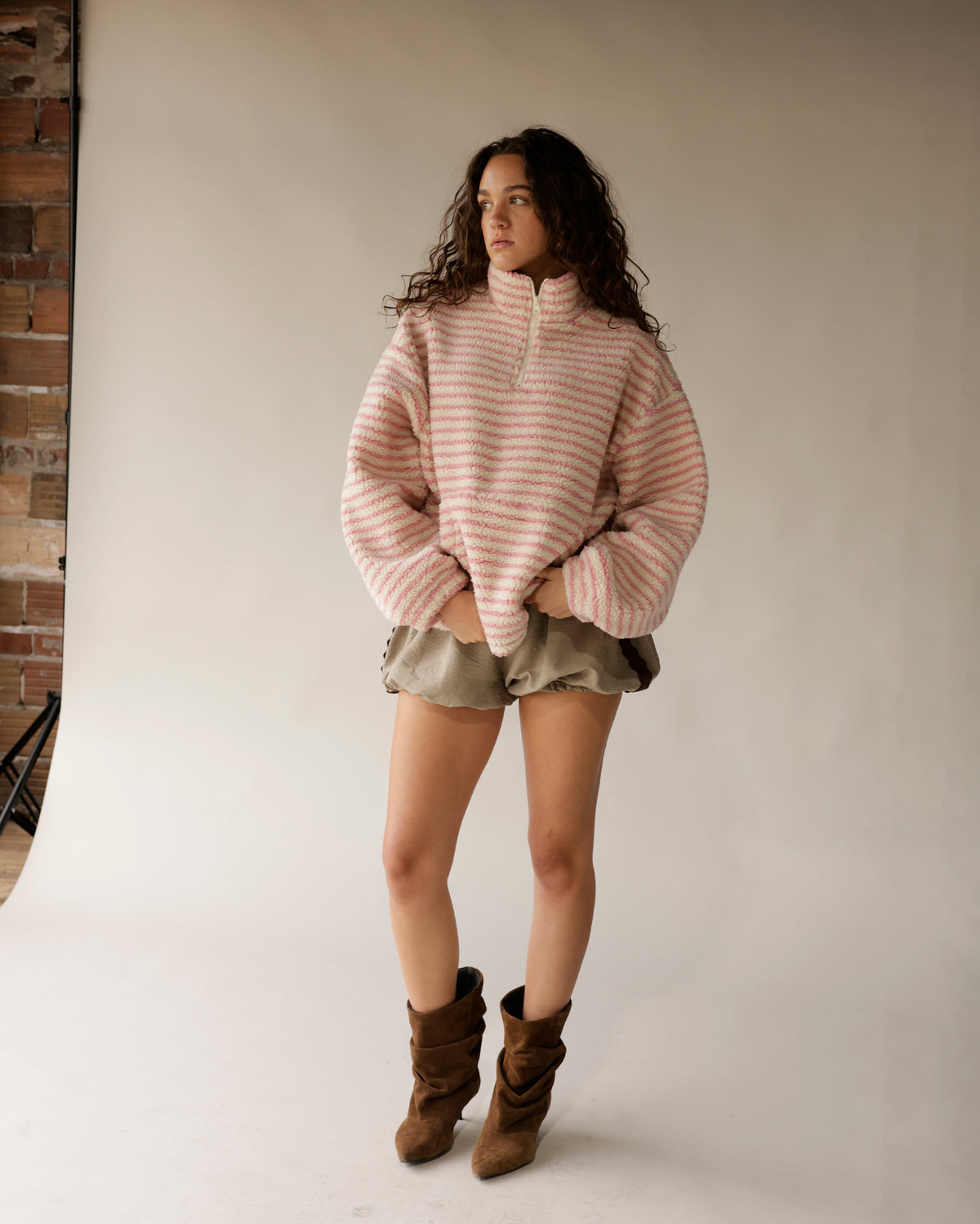 Oversized pink striped sherpa quarter-zip pullover styled with olive shorts and brown boots