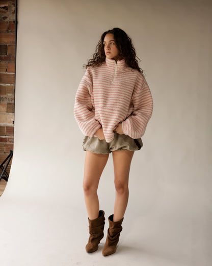 Oversized pink striped sherpa quarter-zip pullover styled with olive shorts and brown boots