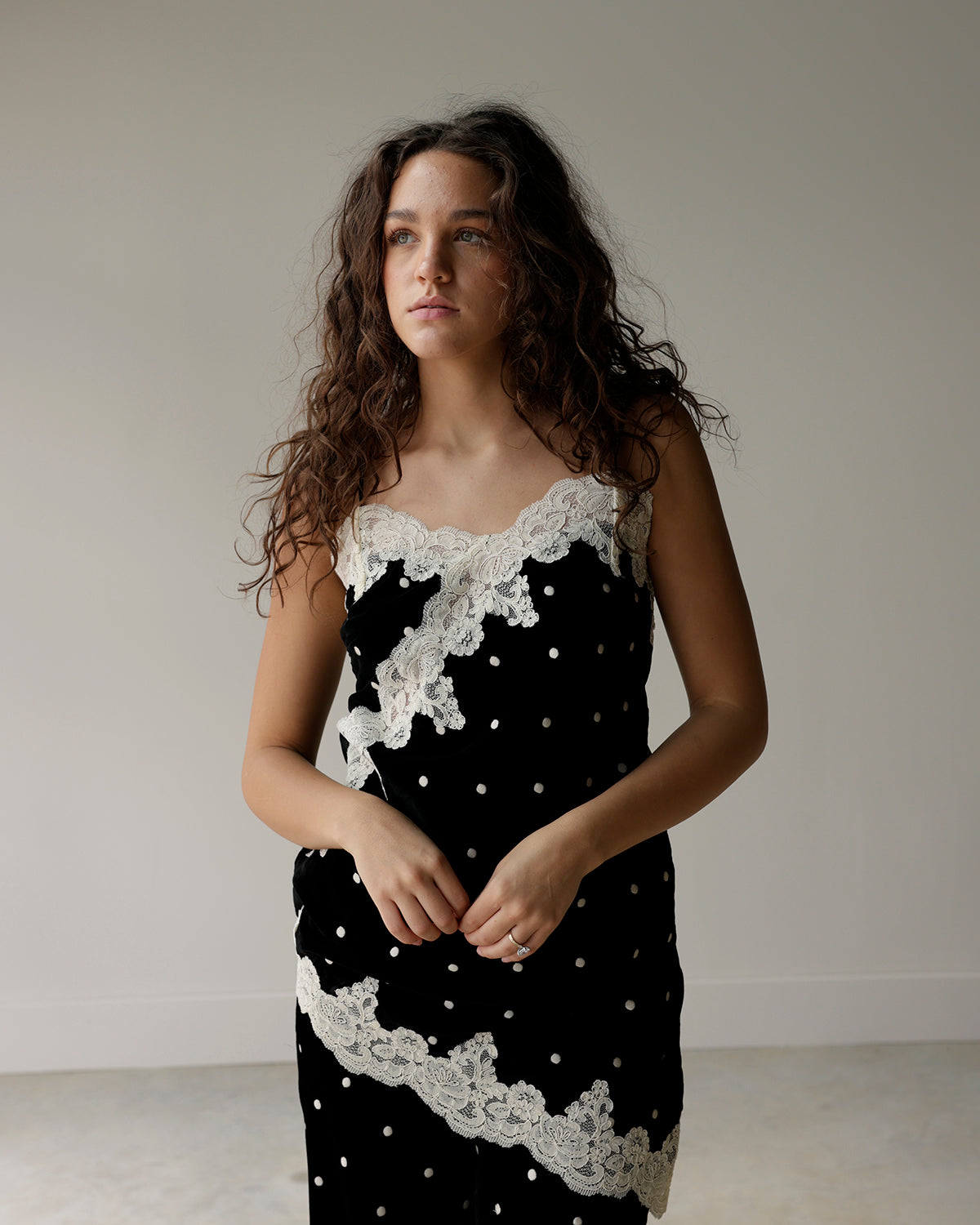 woman wearing a maude black and ivory polka dot camisole top featuring floral lace appliqués, scalloped neckline and asymmetrical lace hem.