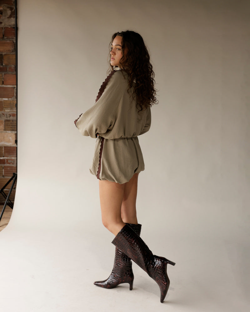 Olive green romper shorts with brown scallop trim, worn with croc knee-high boots