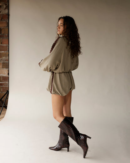 Olive green romper shorts with brown scallop trim, worn with croc knee-high boots