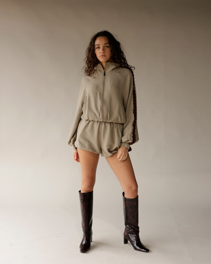 Sage green athletic shorts with elastic waistband, worn with matching zip jacket and dark boots