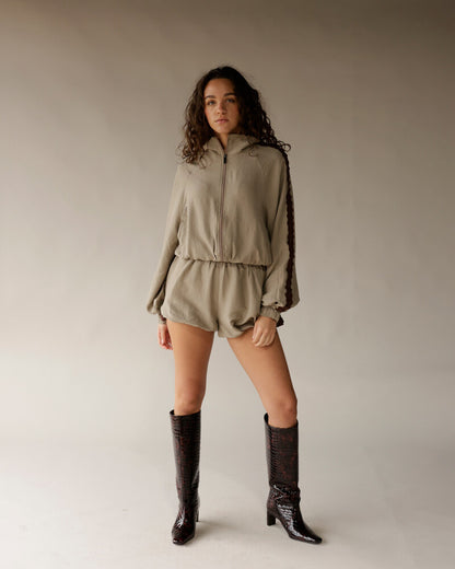Sage green athletic shorts with elastic waistband, worn with matching zip jacket and dark boots