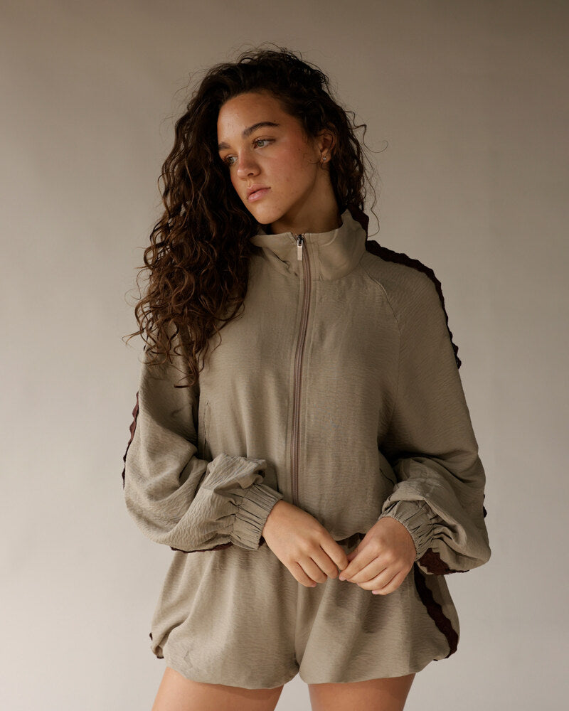 Sage green zip-up track jacket and matching mini shorts set with ruched cuffs