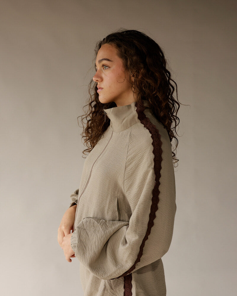 Woman wearing beige textured mock-neck pullover with dark trim side detail