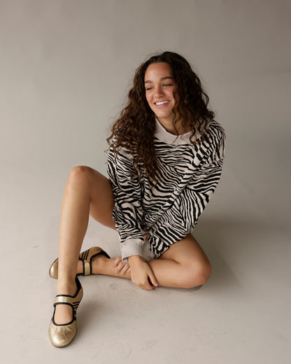 Zebra print reversible mock neck sweatshirt worn with gold Mary Jane flats