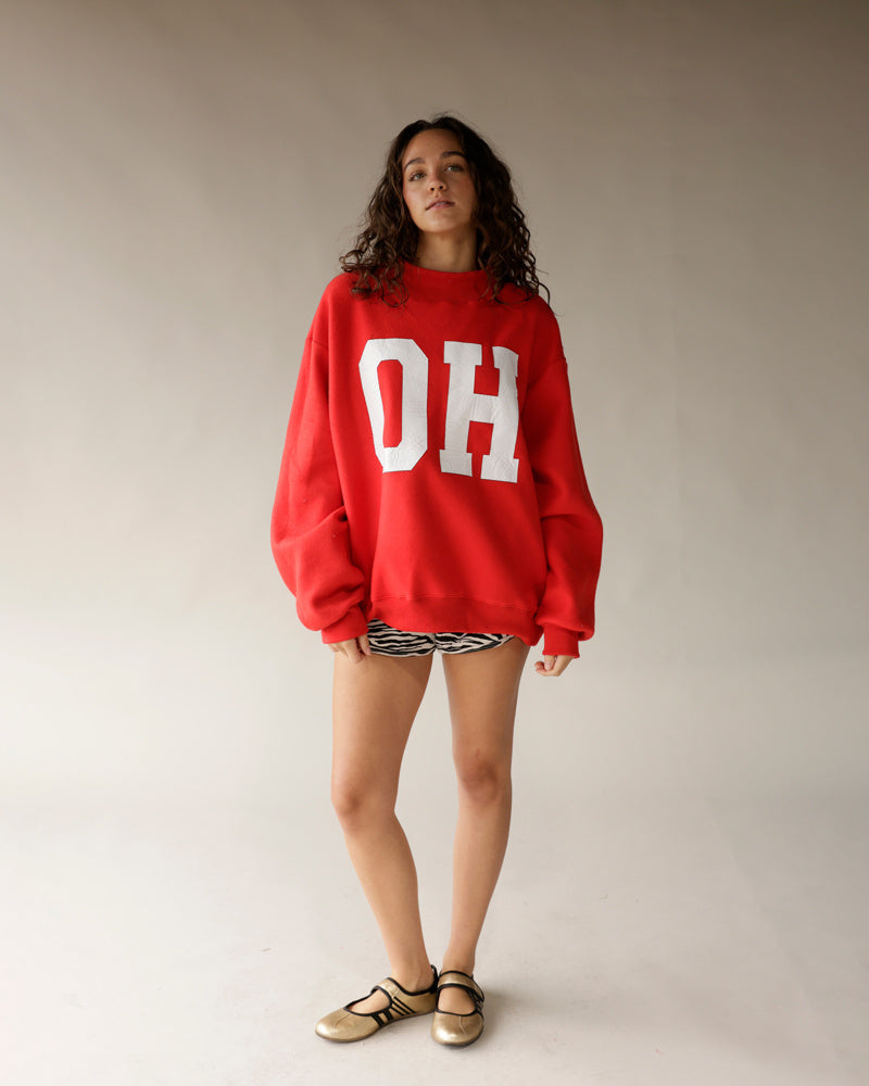 Oversized red crewneck sweatshirt with white OH lettering, worn with zebra shorts