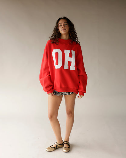 Oversized red crewneck sweatshirt with white OH lettering, worn with zebra shorts