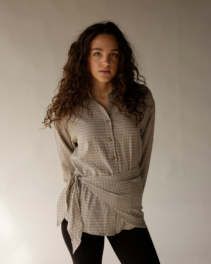 Black capri leggings worn with a belted plaid linen tunic shirt