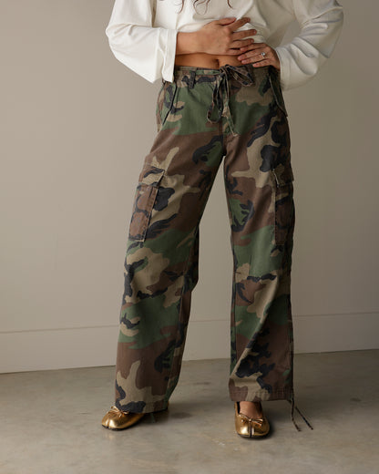 woman wearing veveret woodland camouflage wide-leg cargo pants with oversized flap pockets, tie waistband and metallic gold ballet flats.