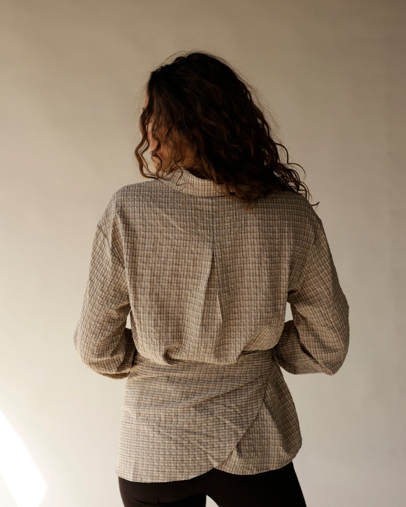 Black capri pants worn with beige plaid long-sleeve shirt, rear view