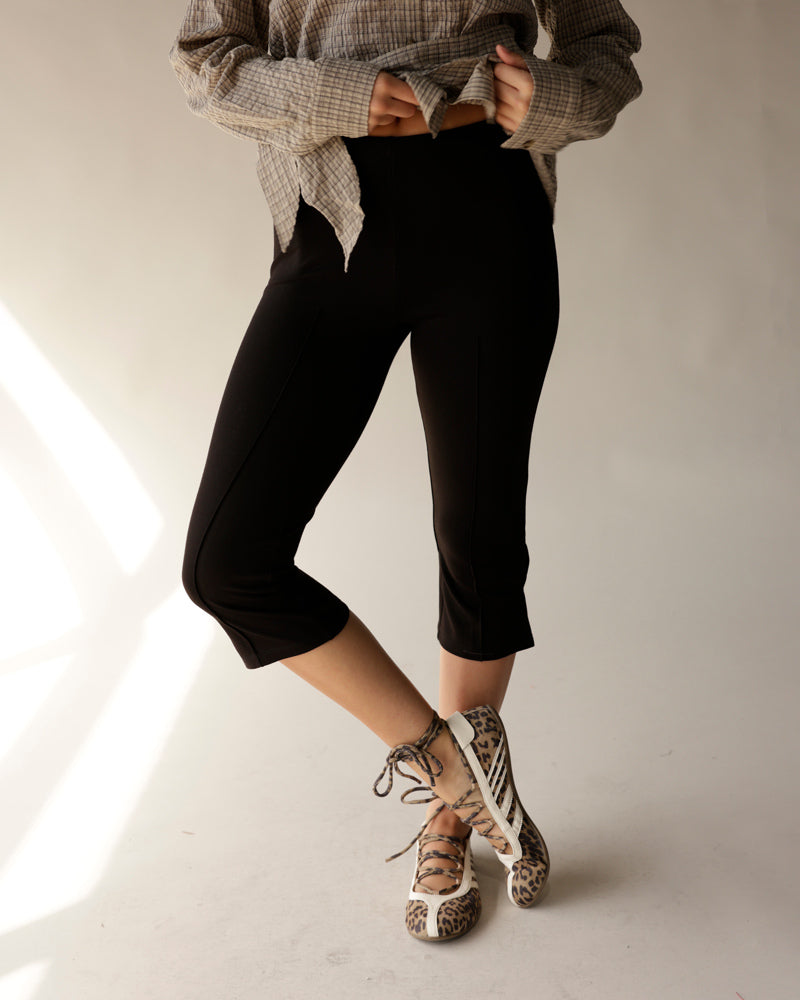 Black capri leggings with fitted silhouette and cuffed hem, styled casually