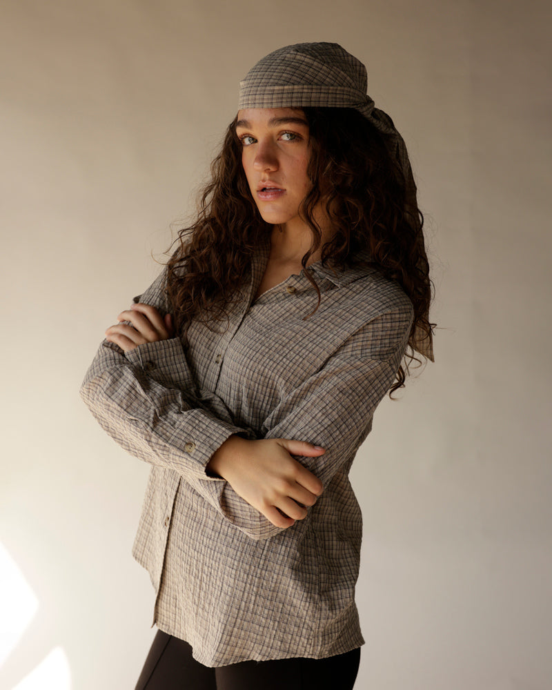 Caramel plaid button-up shirt with matching scarf tied as headwrap, arms crossed