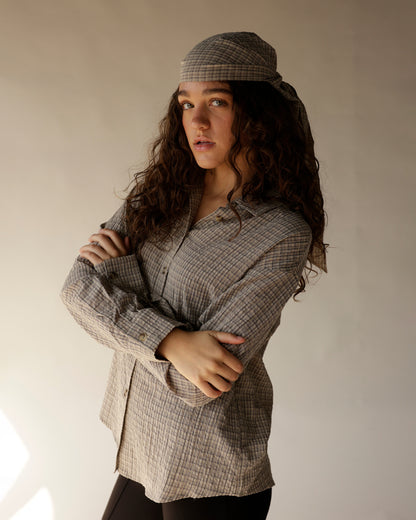 Caramel plaid button-up shirt with matching scarf tied as headwrap, arms crossed