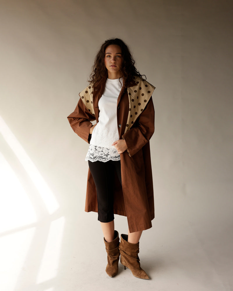 Oversized brown trench coat with detachable polka dot scarf, worn over white lace top