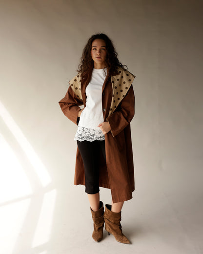 Oversized brown trench coat with detachable polka dot scarf, worn over white lace top