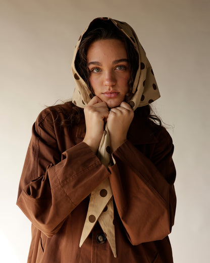 Brown oversized trench coat with beige polka dot detachable headscarf, modeled together