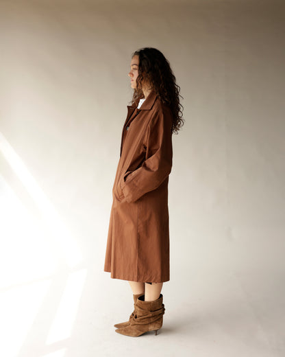Oversized brown trench coat, midi length, worn with tan suede ankle boots, side profile view.