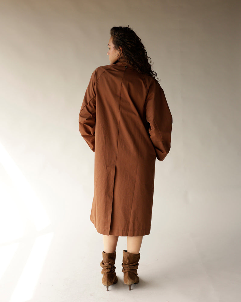 Oversized brown trench coat with back vent, worn with tan suede boots