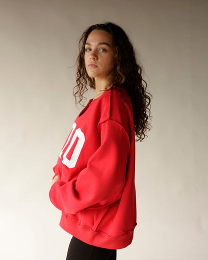 Woman wearing oversized red Ohio crewneck sweatshirt with white block letters