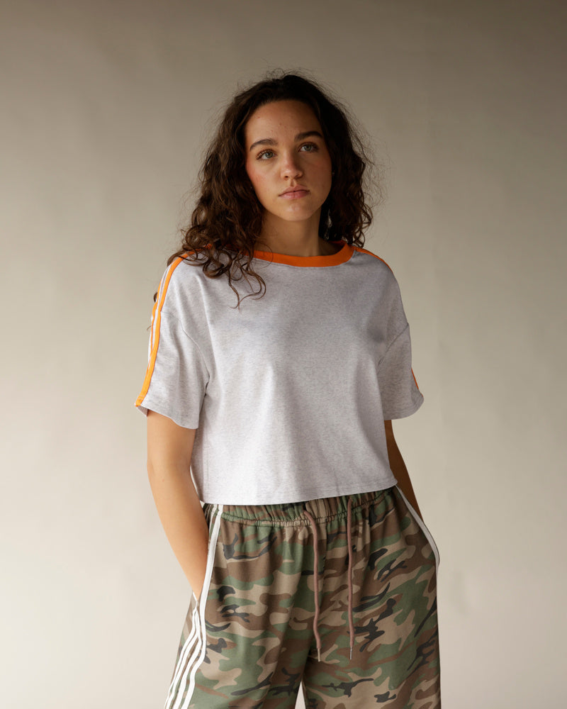 Gray crop tee with orange collar and shoulder stripes, paired with camo pants