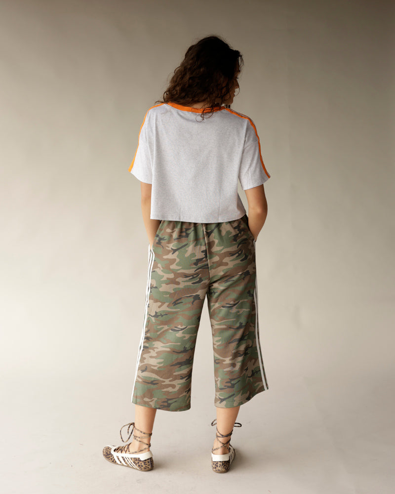White crop tee with orange shoulder stripes, shown with camo culottes, back view