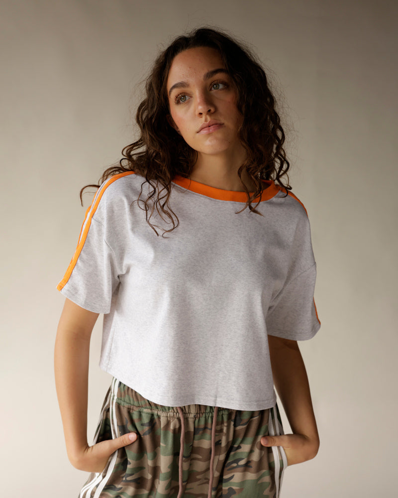 Gray crop tee with orange neckline and shoulder stripes, paired with camo pants