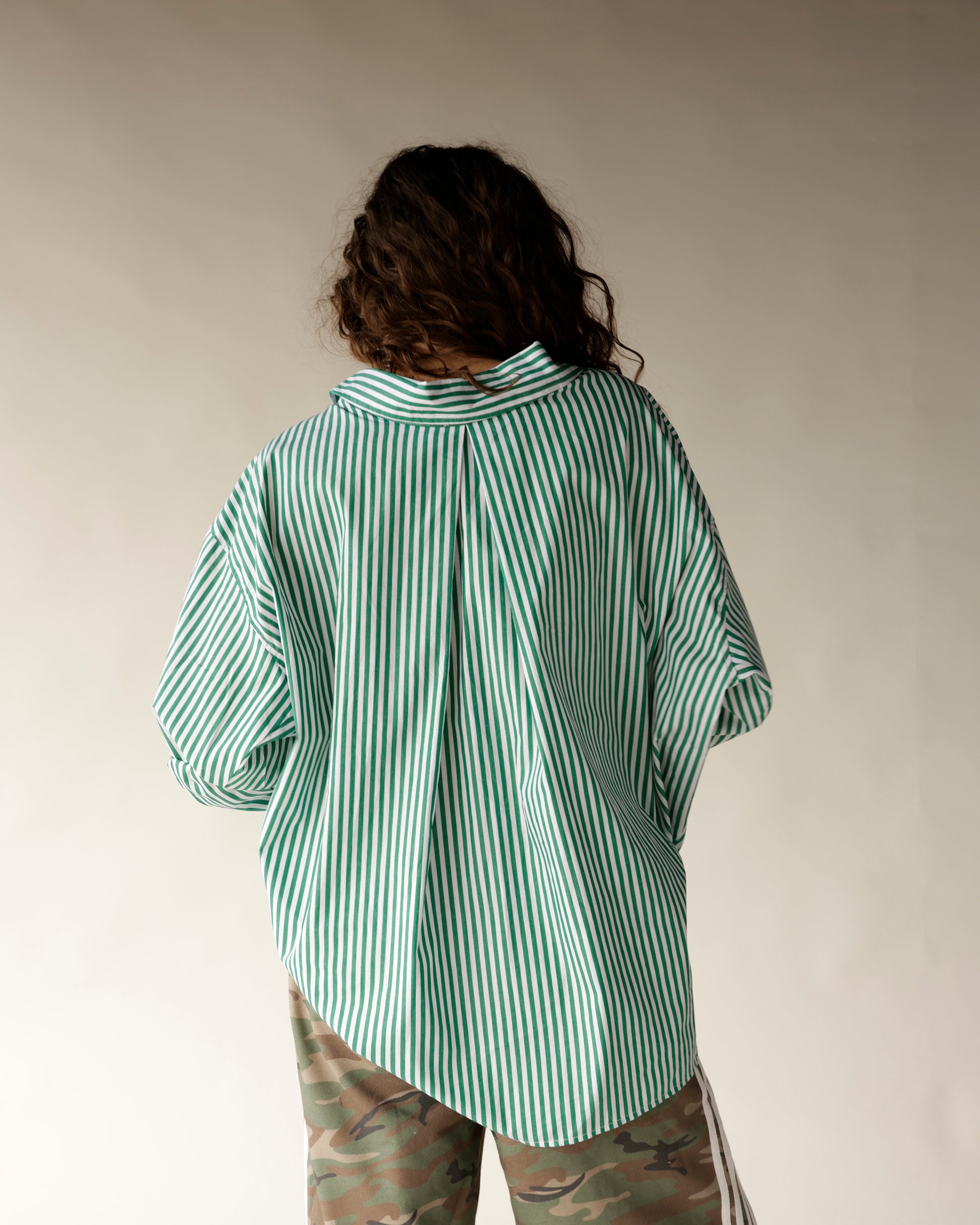 Oversized green and white striped button-up shirt, back view, worn with camo pants