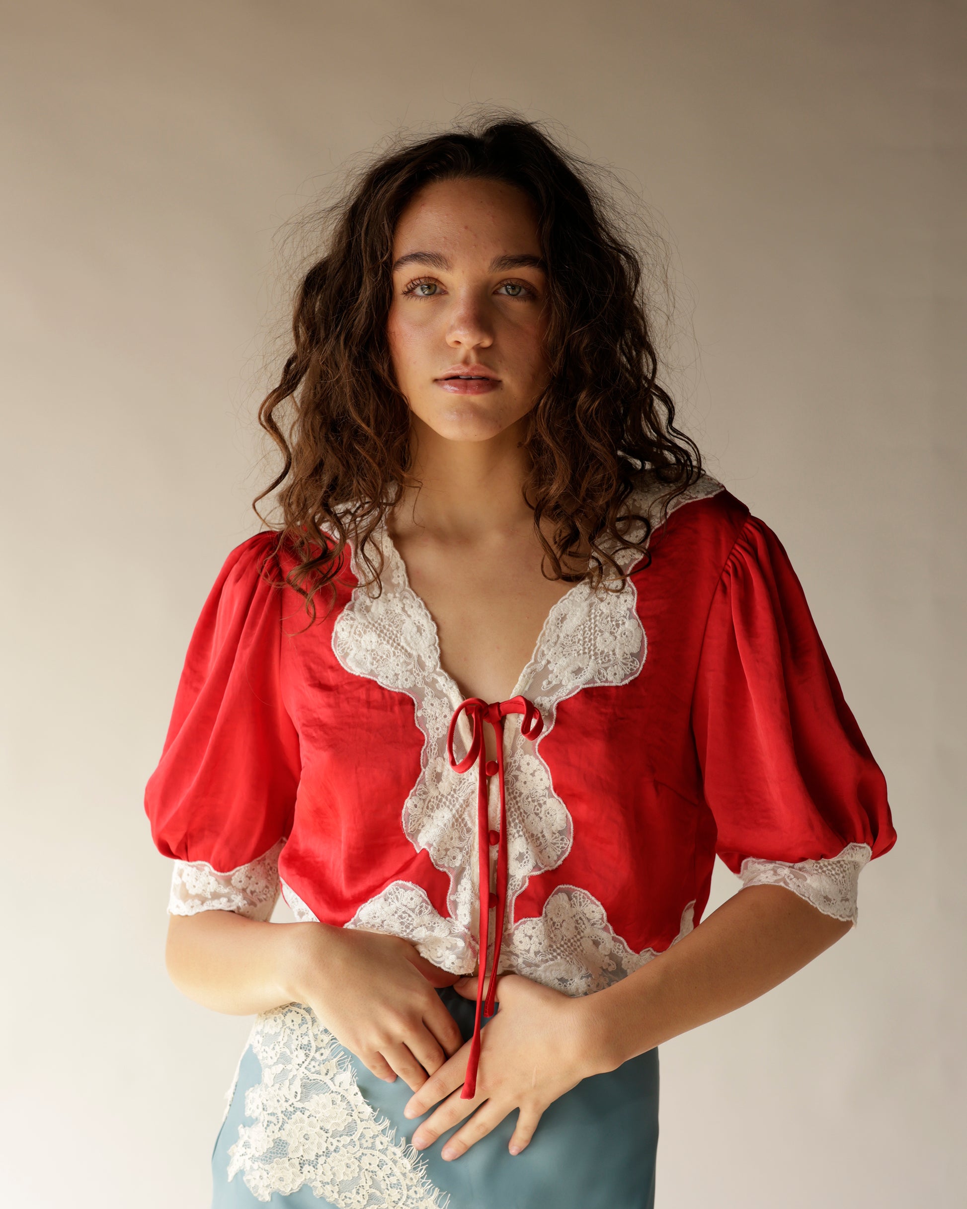 Romantic yet bold, this red lace crop blouse features a deep v-neckline, scalloped lace trim, and puff sleeves. Perfect for a night out or summer date.