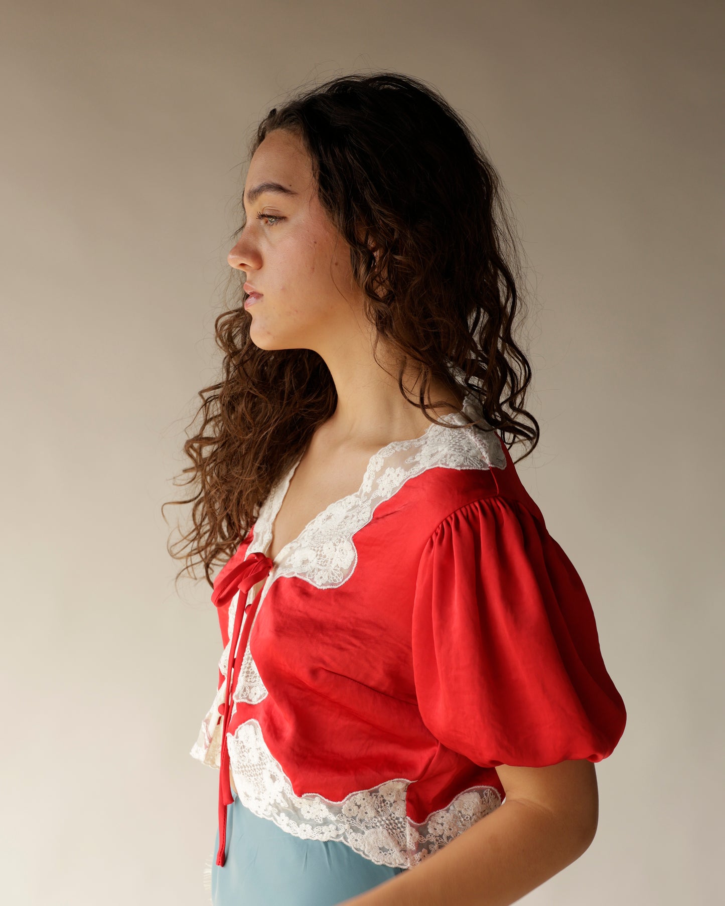 Red satin crop top with white lace trim and puff sleeves, tied front