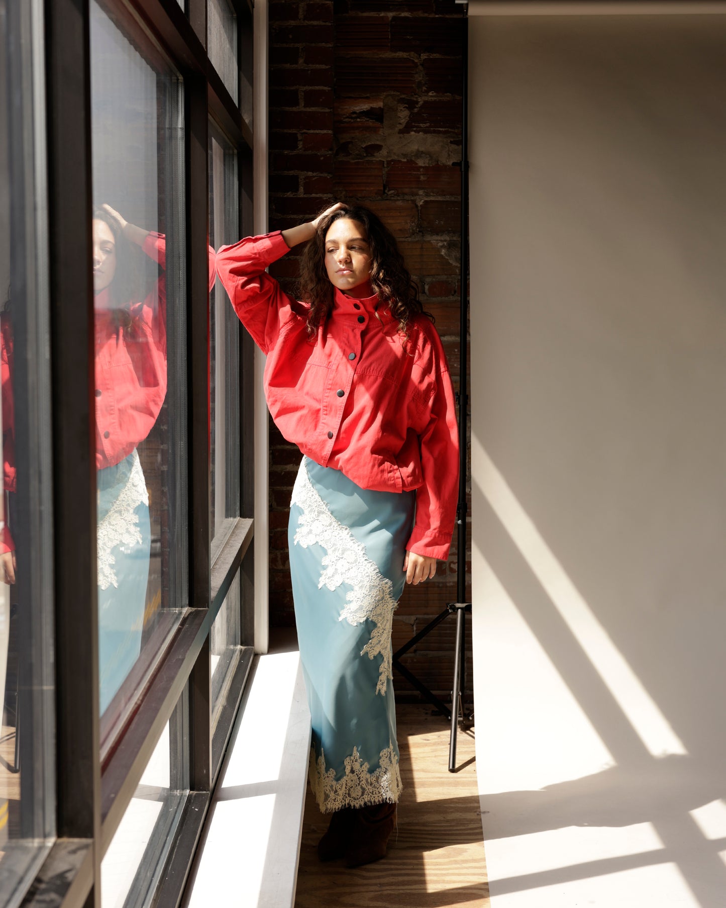 Dusty blue satin midi skirt with white lace trim, paired with red jacket