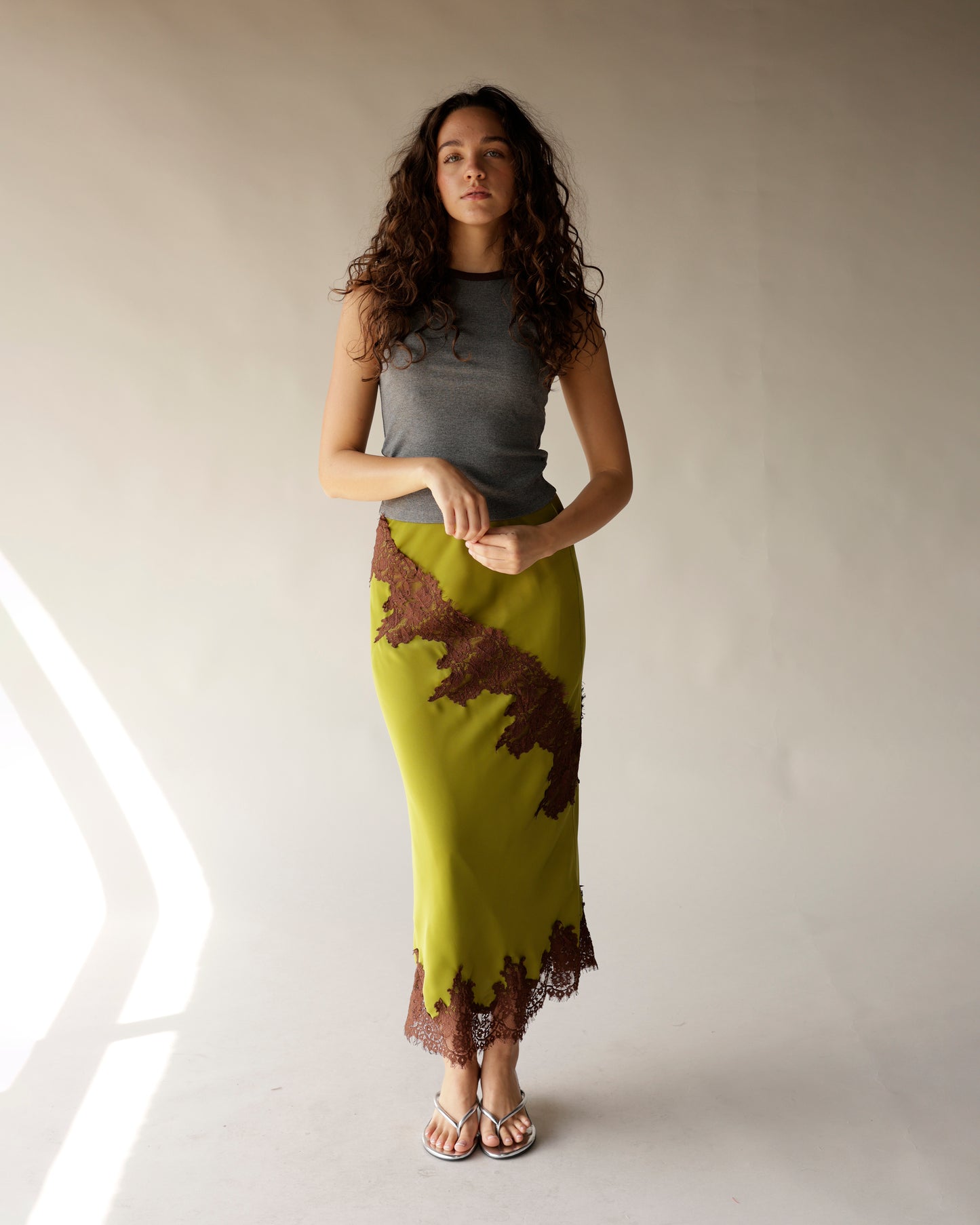 Olive green satin midi skirt with brown lace trim and diagonal lace appliqué detail