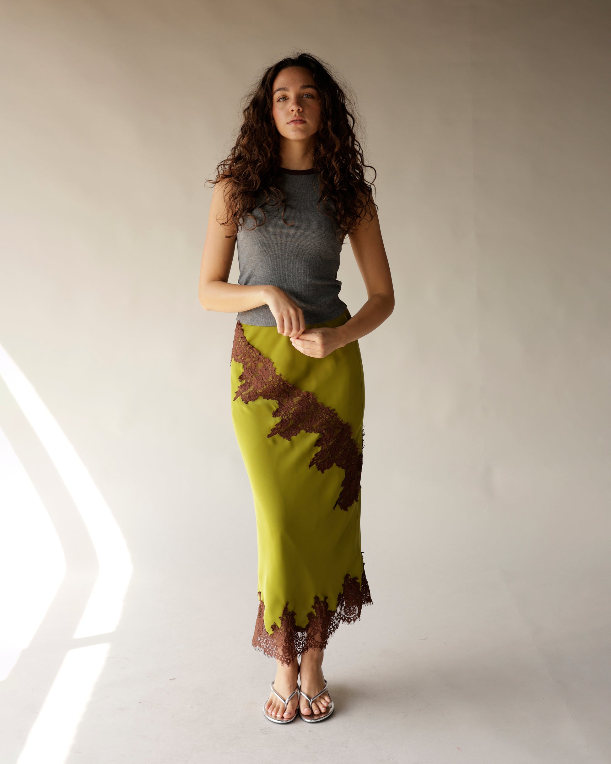 Olive green satin midi skirt with brown lace trim and diagonal lace appliqué detail