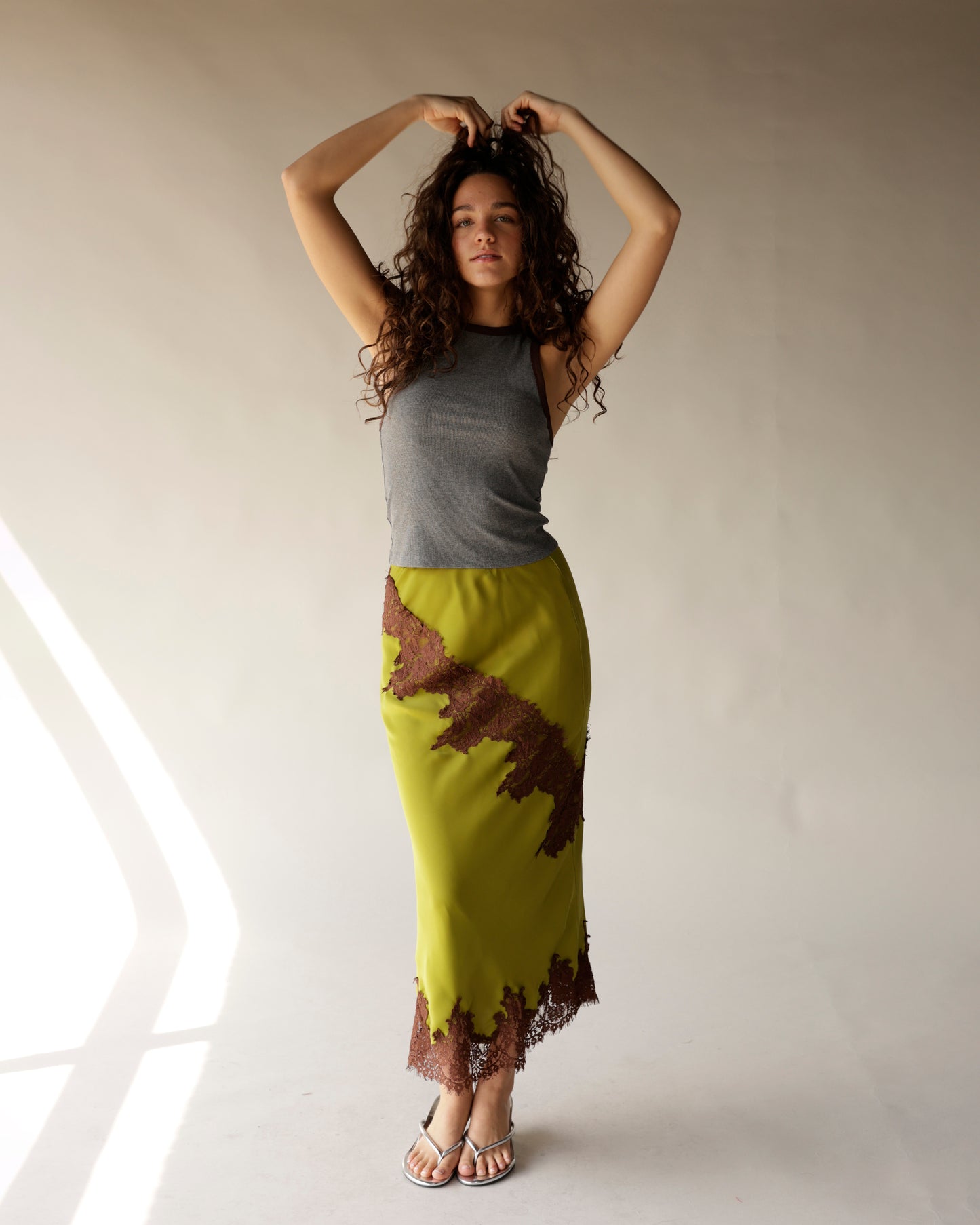 Olive green satin midi skirt with brown lace trim detailing and asymmetric hem
