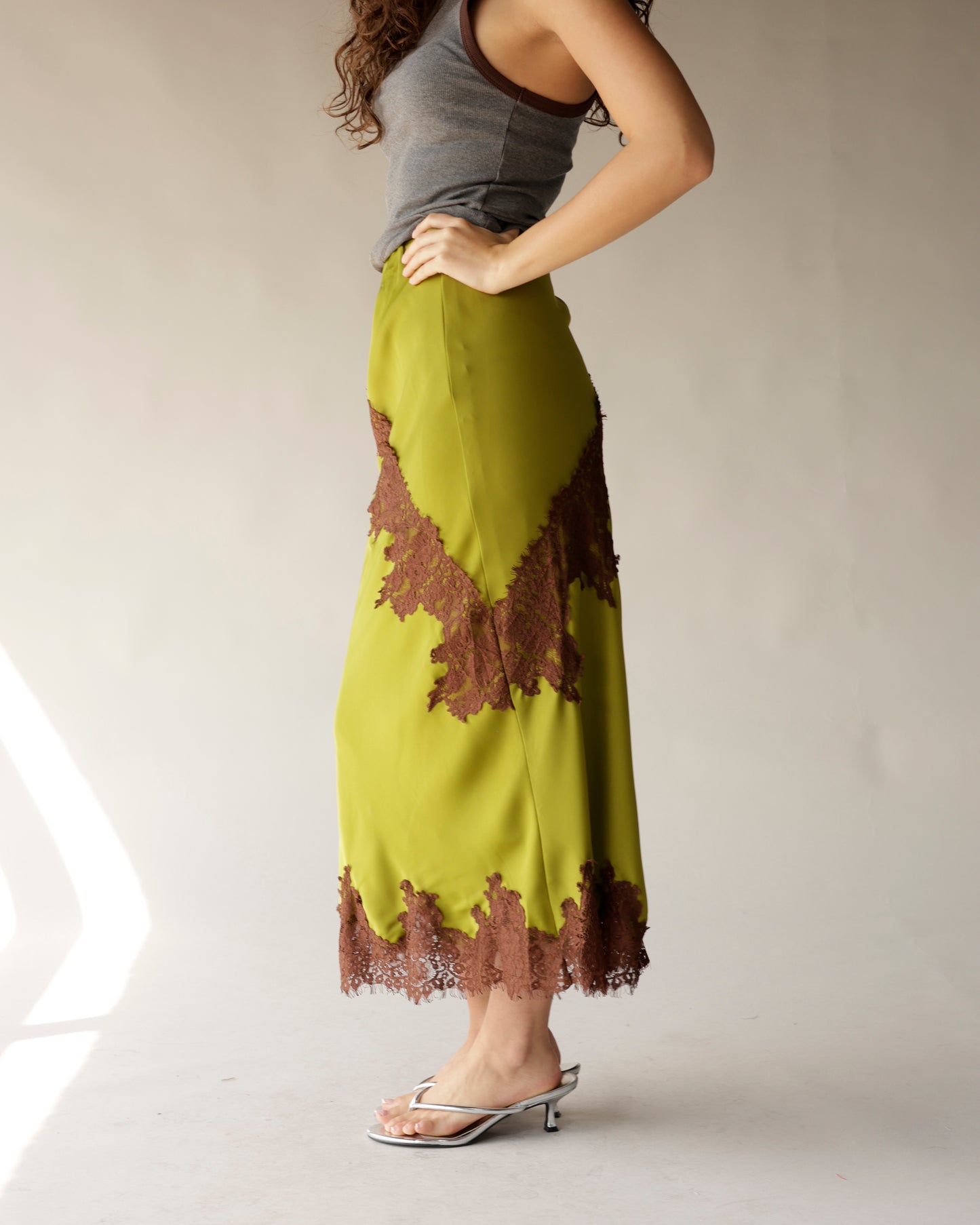Olive green satin midi skirt with brown lace appliqué trim and hem detail