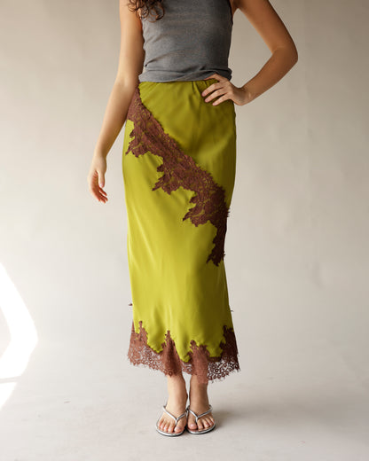 Exude vintage charm in this olive green, satin midi skirt with a diagonal brown lace appliqué and scalloped hem. Perfect for any occasion.