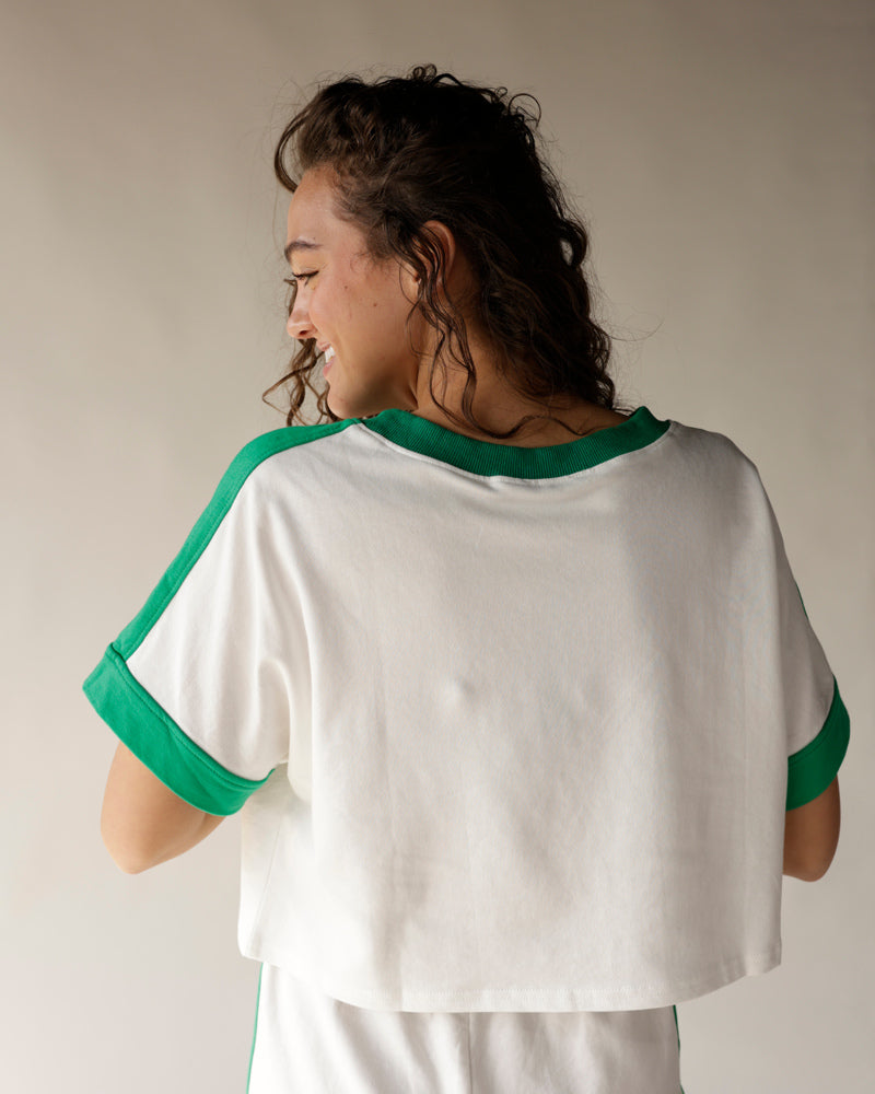 White crop tee with green contrast trim at neckline, sleeves, and cuffs