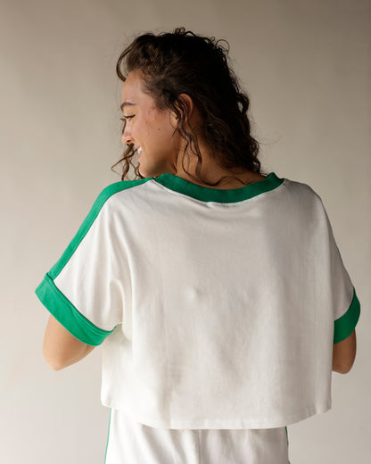 White crop tee with green contrast trim at neckline, sleeves, and cuffs