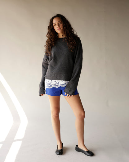 Cobalt blue track shorts worn with gray sweater and white lace underlayer