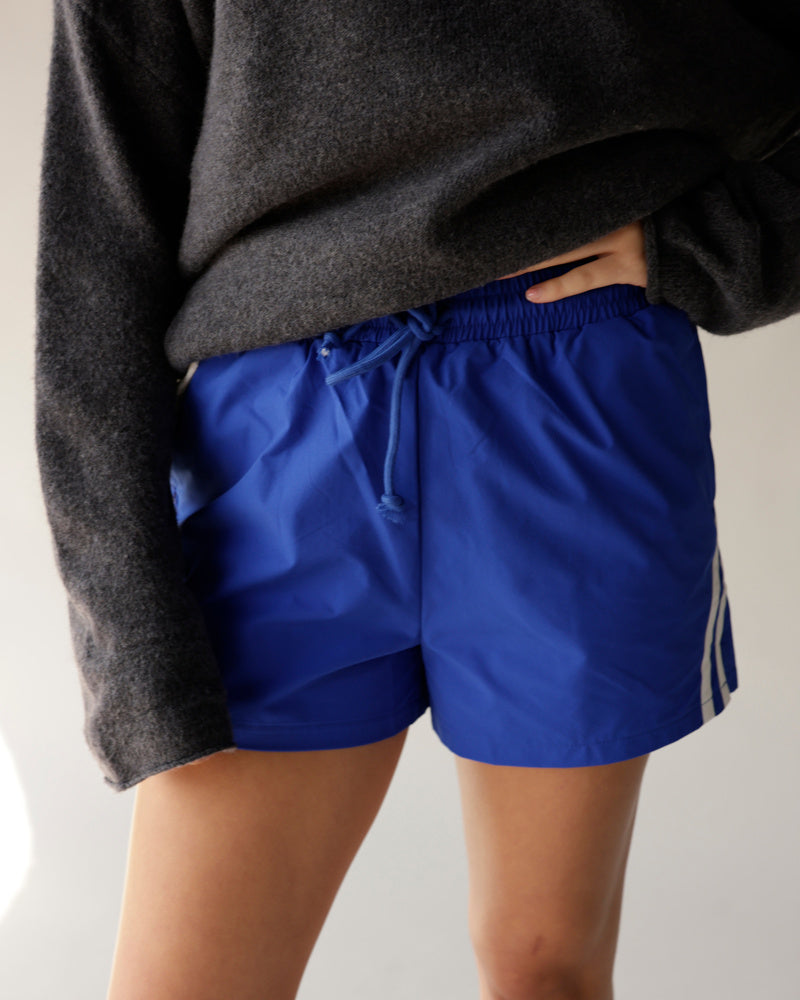 Royal blue athletic track shorts with white side stripes and drawstring waist